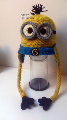 a crocheted yellow and blue hat with googly eyes sitting on top of a plastic container