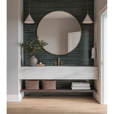 a bathroom with a round mirror above the sink and two baskets under it on the counter