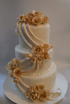 a three tiered wedding cake with flowers on the top and sides, sitting on a white plate