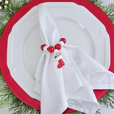 a white plate topped with a red and white napkin next to a christmas tree branch