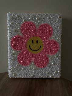 a pink flower with a smiley face painted on it's center is sitting on a table