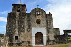 an old stone church with two towers and crosses on the top, surrounded by green grass