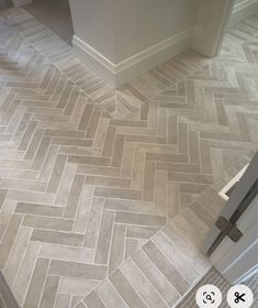 an image of a bathroom floor that looks like herringbones in grey tones with white trim