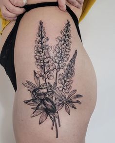 a woman's thigh with flowers on it and a bee sitting on the flower