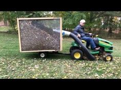 a man riding on the back of a green lawn mower next to a beehive