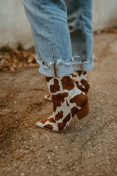 The Caty Western-inspired ankle boot is a legacy style that has transcended over the seasons. With quality craftsmanship and lux materials, these boots only get better with each wear. Details: Cow hair upper. Manmade outsole. 7 in / 17.78 cm shaft height. 10 in / 25.4 cm topline circumference. 2.5 in/6.35 cm heel. Textile lining. Padded insole. Zipper closure. Leather stacked heel. Fit true to size. How To Style Cow Print Boots, Cow Print Boots Outfit, Cow Print Boots, Ariat Cow Print Boots, Cowprint Ankle Boots, Western Mid-calf Boots With Stacked Heel, Black And White Cow Print Boots, Print Boots Outfit, Holiday Gift Box