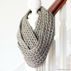 a gray knitted scarf hanging on the side of a wooden bannister next to a white mannequin