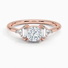 a rose gold engagement ring with three baguets on the band and an oval diamond center