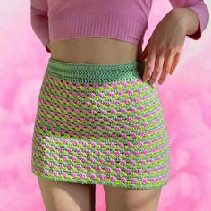 a close up of a person wearing a pink shirt and green crochet skirt