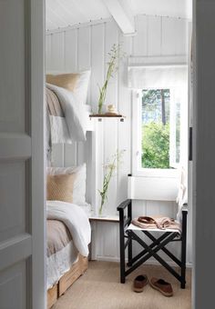 a bedroom with white walls and wood flooring has a bench in front of the window