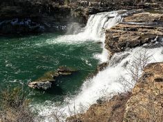 a waterfall with green water and rocks in the foreground