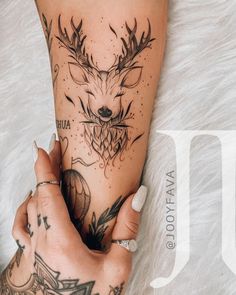 a woman's leg with tattoos on it and a deer head tattooed to the side