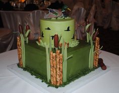 a large green cake with birds on top sitting on a white tablecloth covered table