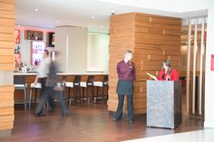 two people standing at a podium in front of a bar