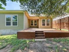 a house with a deck in front of it and grass around the back yard area