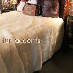 a bed with white fur and pillows on it