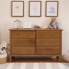 two teddy bears sitting on top of a wooden dresser next to pictures and other items