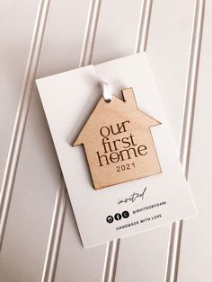 a wooden house ornament with the words our first home on it hanging from a card