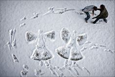 two people are standing in the snow with their handprints on them and one person is kneeling down