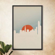 an art print of the san francisco skyline in orange and blue, framed on a wall