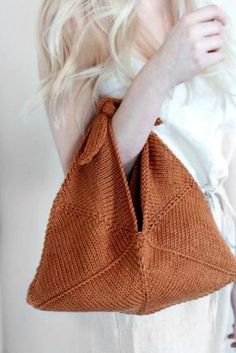 a woman holding a brown knitted bag