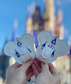 the person is holding two mickey mouse ears in front of disney world's castle