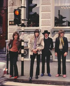 the rolling stones posing for a photo in front of an old building with a traffic light