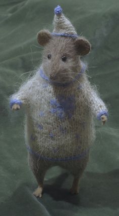 a stuffed rat is wearing a knitted hat and blue ribbon around it's neck