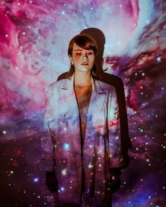 a woman standing in front of a colorful background with stars and planets on the wall