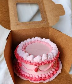 a pink and white cake in a brown box