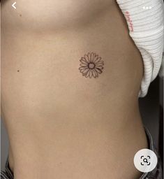 a woman's stomach with a small flower tattoo on the side of her belly