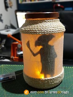 a mason jar with a shadow of a woman on it and rope wrapped around the lid