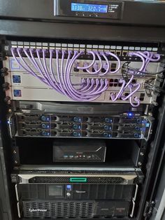 several servers are stacked on top of each other with purple cords attached to the sides