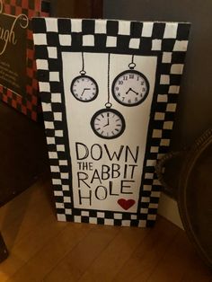 a sign with clocks hanging from it's sides that says down the rabbit hole