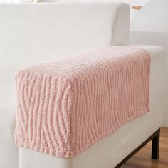 a white couch with a pink blanket on it