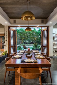 a dining room table set with plates and place settings in front of an open window