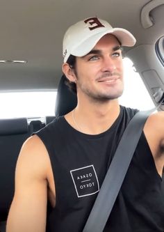 a man sitting in the back seat of a car wearing a white hat and black shirt