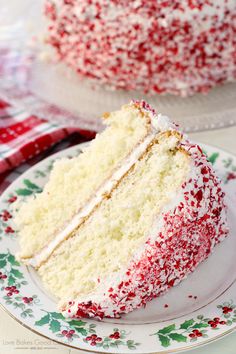 a slice of cake with white frosting and red sprinkles on a plate