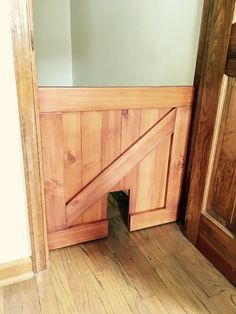 an open wooden door in the corner of a room with wood flooring and walls