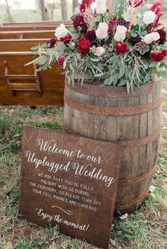 a wooden barrel with flowers in it and a welcome sign