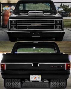 the back end of a black truck parked in a parking lot next to a fence