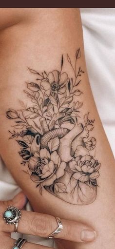 a woman's thigh with flowers on it and a heart in the middle is shown