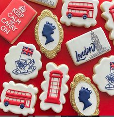 some decorated cookies are on a red table and one has a british flag, the other is a london bus