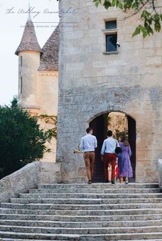 two people are walking up the stairs to an old castle like building with stone steps