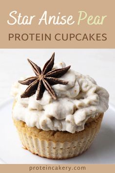 a cupcake with white frosting and anise star on top, sitting on a plate