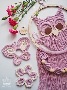 an owl is made out of yarn and some flowers are on the table next to it