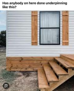 a mobile home with steps leading up to the front door and windows on each side