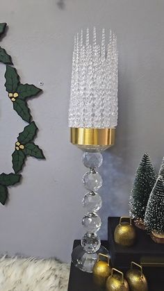 a tall glass candle holder sitting on top of a table next to christmas trees and ornaments