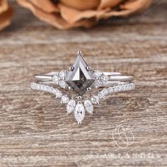 an engagement ring with a pear shaped diamond surrounded by smaller pears on a wooden surface