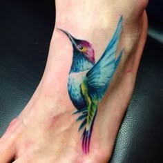 a colorful hummingbird tattoo on the foot